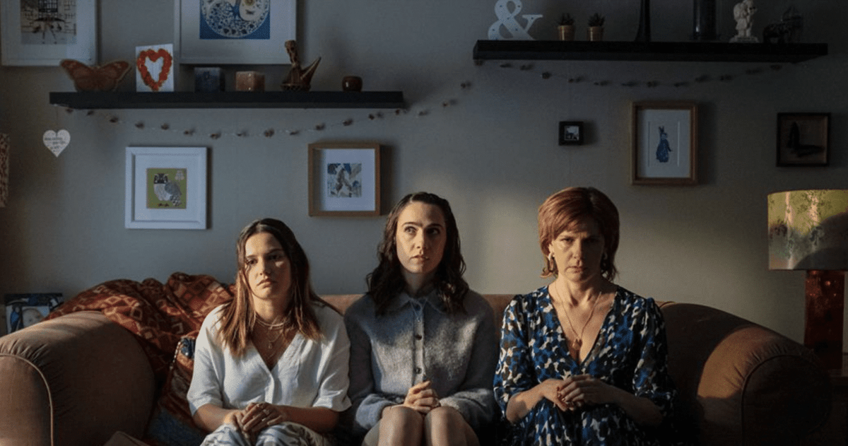 Two younger women and one older woman sit on a sofa looking dejected in a publicity still for Such Brave Girls on Stan.