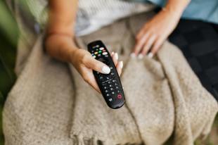 hand holding remote control. Photo by Kaboom pics.